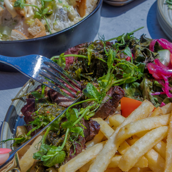 Gluten Free Flat Iron Steak cooked Medium Rare and served with garden salad, fries & beef fat chimichurri